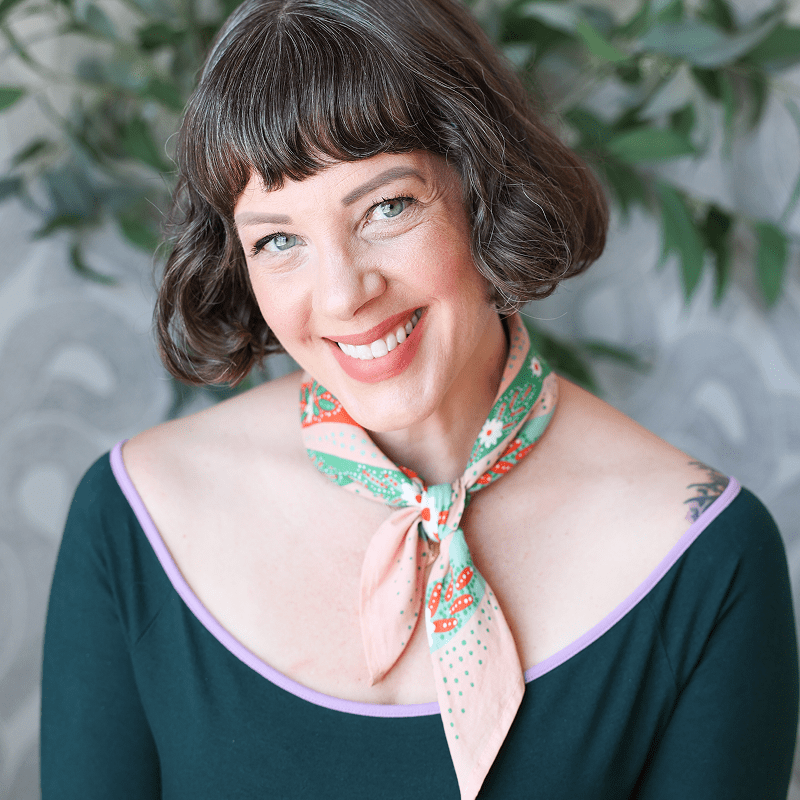 Smiling woman with short hair and scarf.