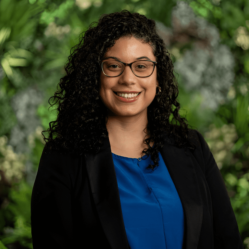 Smiling person with curly hair and glasses.